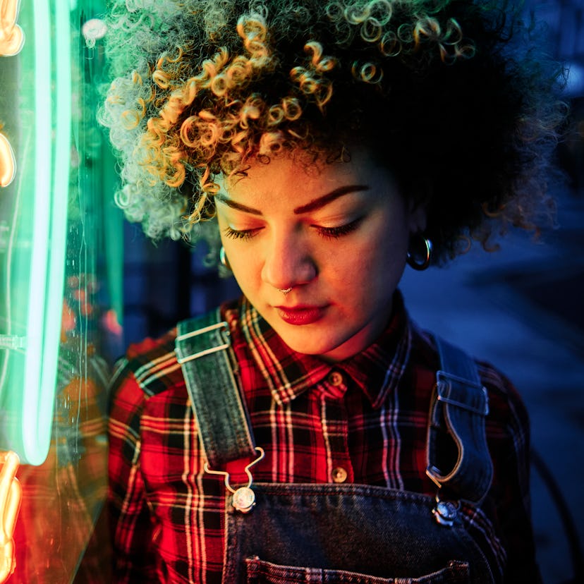 Young woman standing in neon light, embracing the spiritual meaning of the November 2021 full blood ...