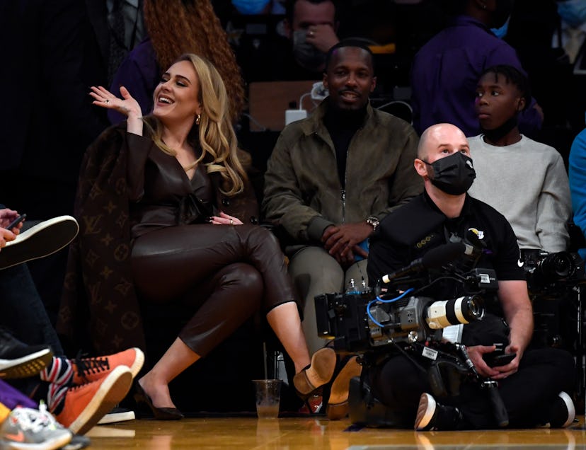 Adele in a leather blazer, pants, and Louis Vuitton coat at a basketball game. 