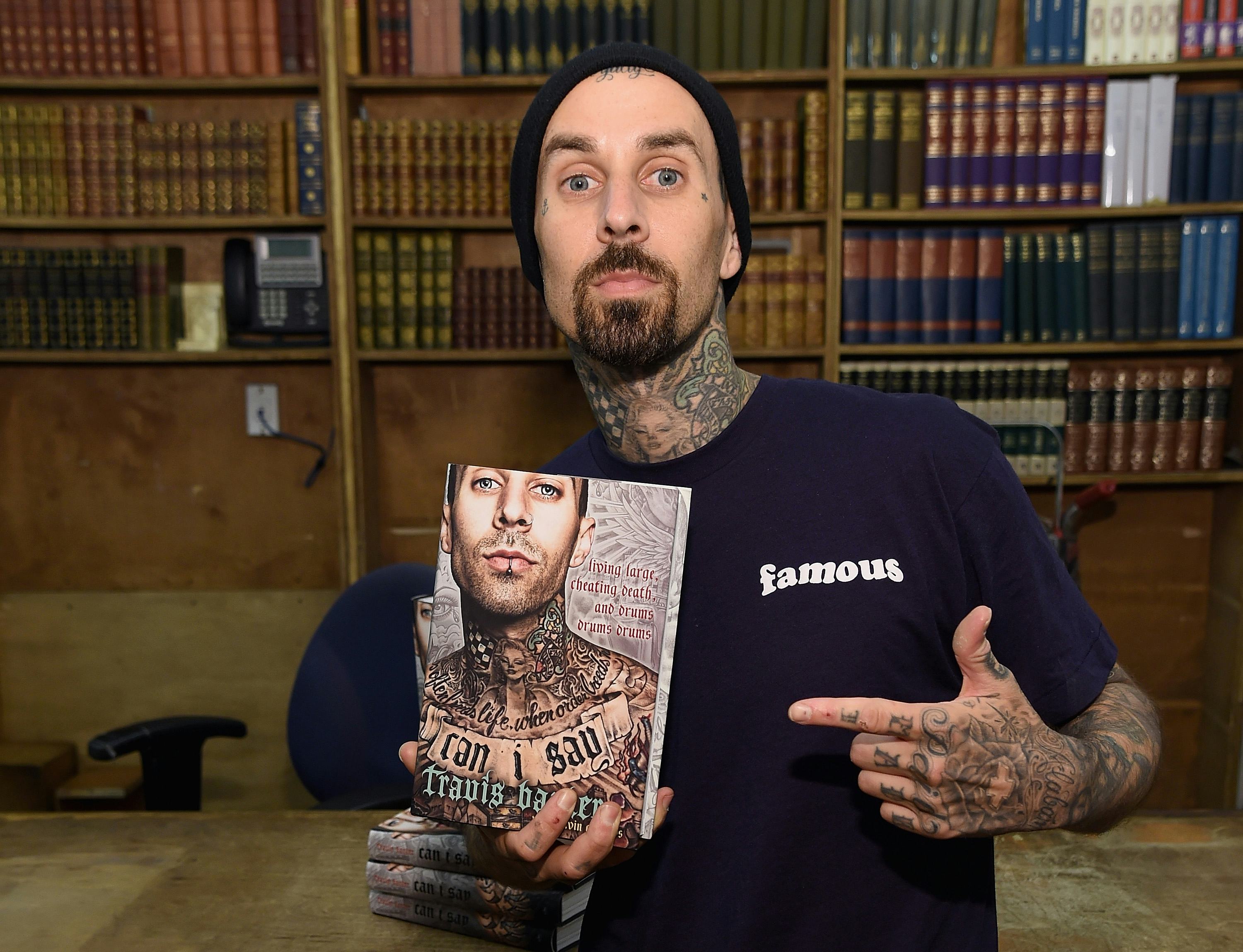 Travis Barker holding his memoir in 2016.