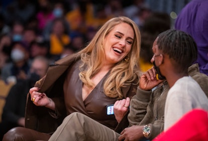 Adele in a leather blazer, pants, and Louis Vuitton coat at a basketball game. 