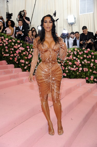 Kim Kardashian West at the Met Gala in a nude dress with jewels made to look like rain drops falling...