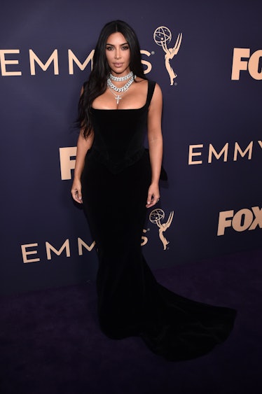 Kim Kardashian attends the Emmy Awards in a black gown with a deep neckline and a chunky necklace 