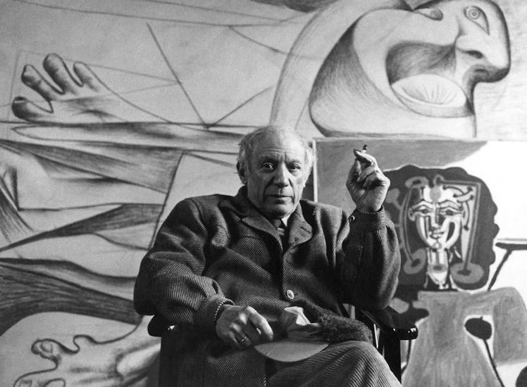 Portrait of Spanish artist Pablo Picasso (1881 - 1973) as he smokes a cigarette, seated in front of ...
