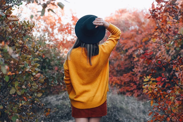Young woman standing in autumn forest, thinking about how her unlucky zodiac sign will have the wors...