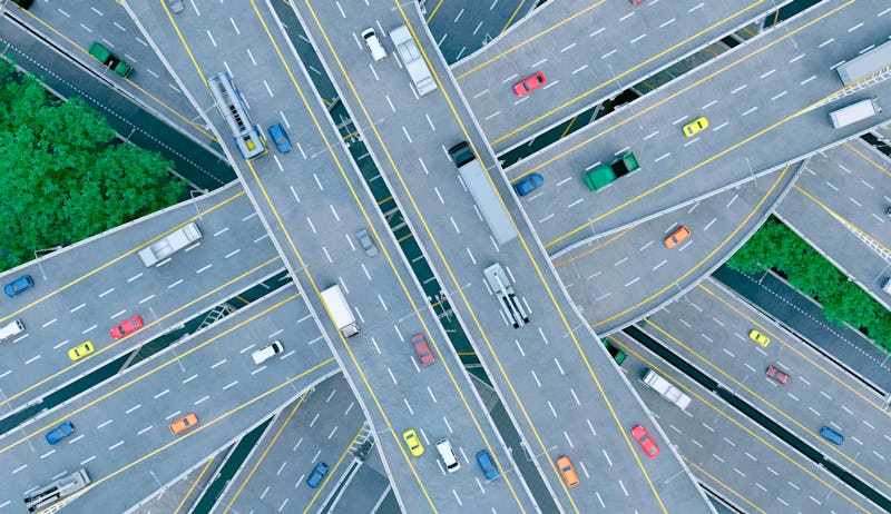 Cars, busses and trucks drive on multiple lane highways. Seen from above. Concept of mobility. 
The ...