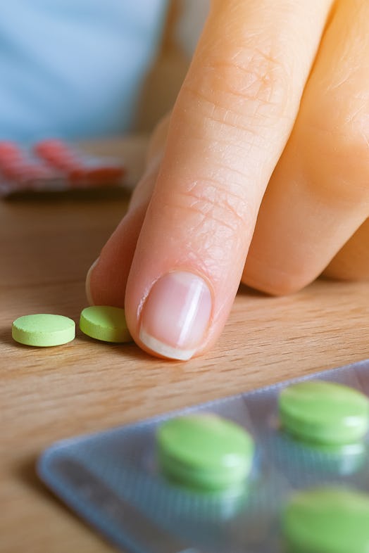 A girl or woman takes Pills from a wooden kitchen table. Take vitamins, painkillers, medications, an...