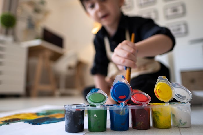 Happy little baby artist drawing with colorful paints at home