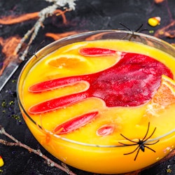 A nonalcoholic halloween punch with a large red ice cube in the shape of a hand.