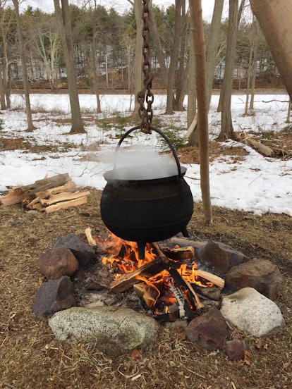 Black cauldron over wood burning fire outdoors