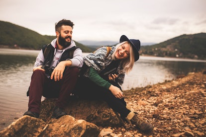 Young smiling couple enjoying nature and their hiking together, which is one idea for fall couple pi...