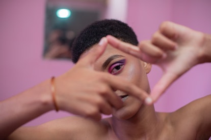 Portrait of young queer male making a photograph gesture with his hands
