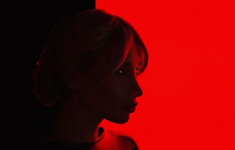 Studio Portrait a young blonde transgender woman in latex on a red glowing background