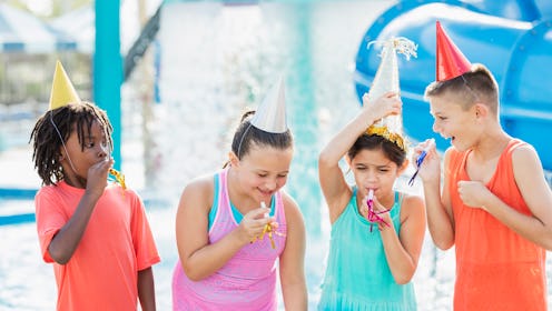 A multi-ethnic group of four children, 8 and 9 years old, having fun together, at a birthday party a...