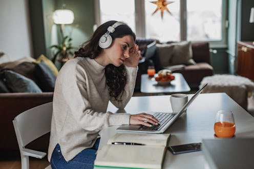 Young woman at home, looking at the laptop and feeling worried