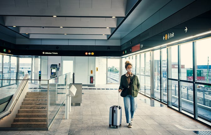 Shot of a masked young woman travelling through a subway station