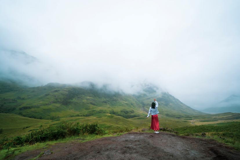 One female tourist explore the  Three Sisters mountain range in mist day,Glencoe,Scotland,UK
