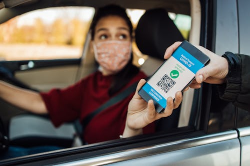 A woman in a car shows her vaccine passport app.