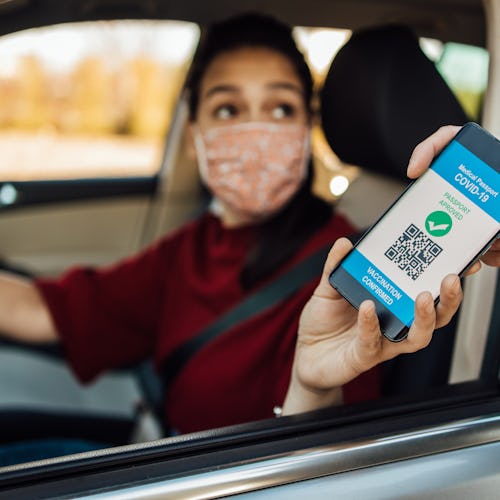 A woman in a car shows her vaccine passport app.