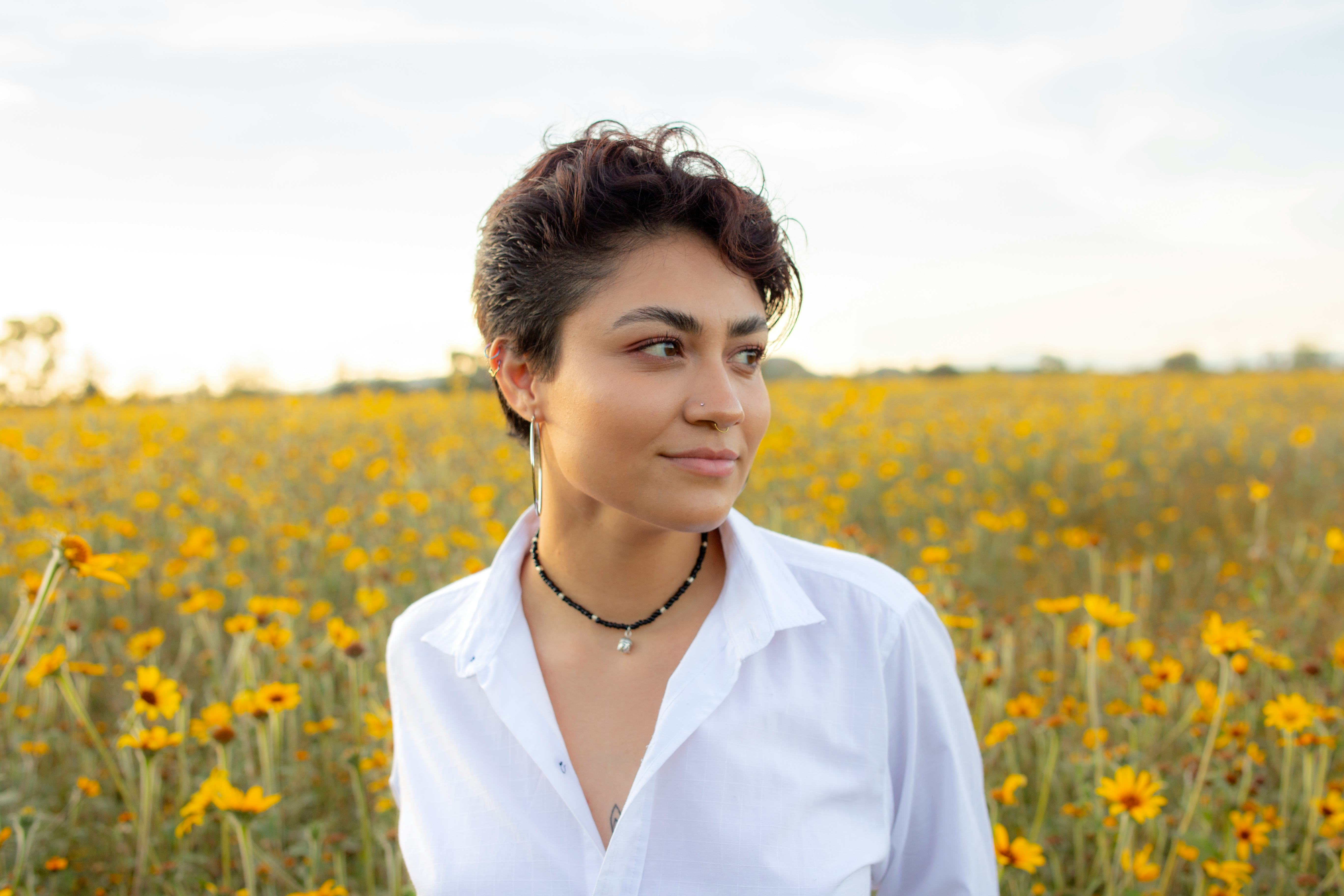 A woman with short hair stands in a field of sunflowers. The Scorpio new moon is all about focusing ...