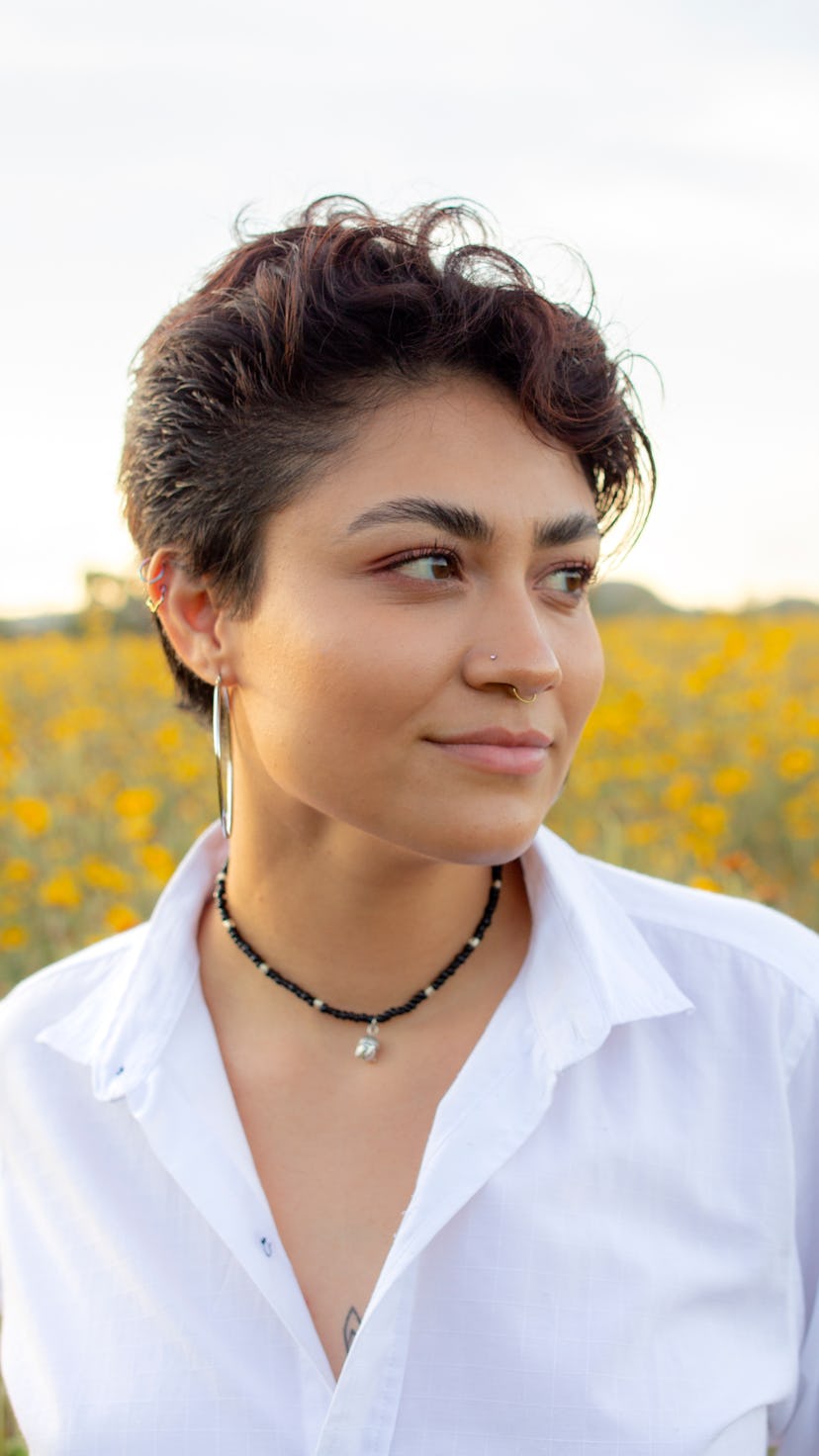 A woman with short hair stands in a field of sunflowers. The Scorpio new moon is all about focusing ...