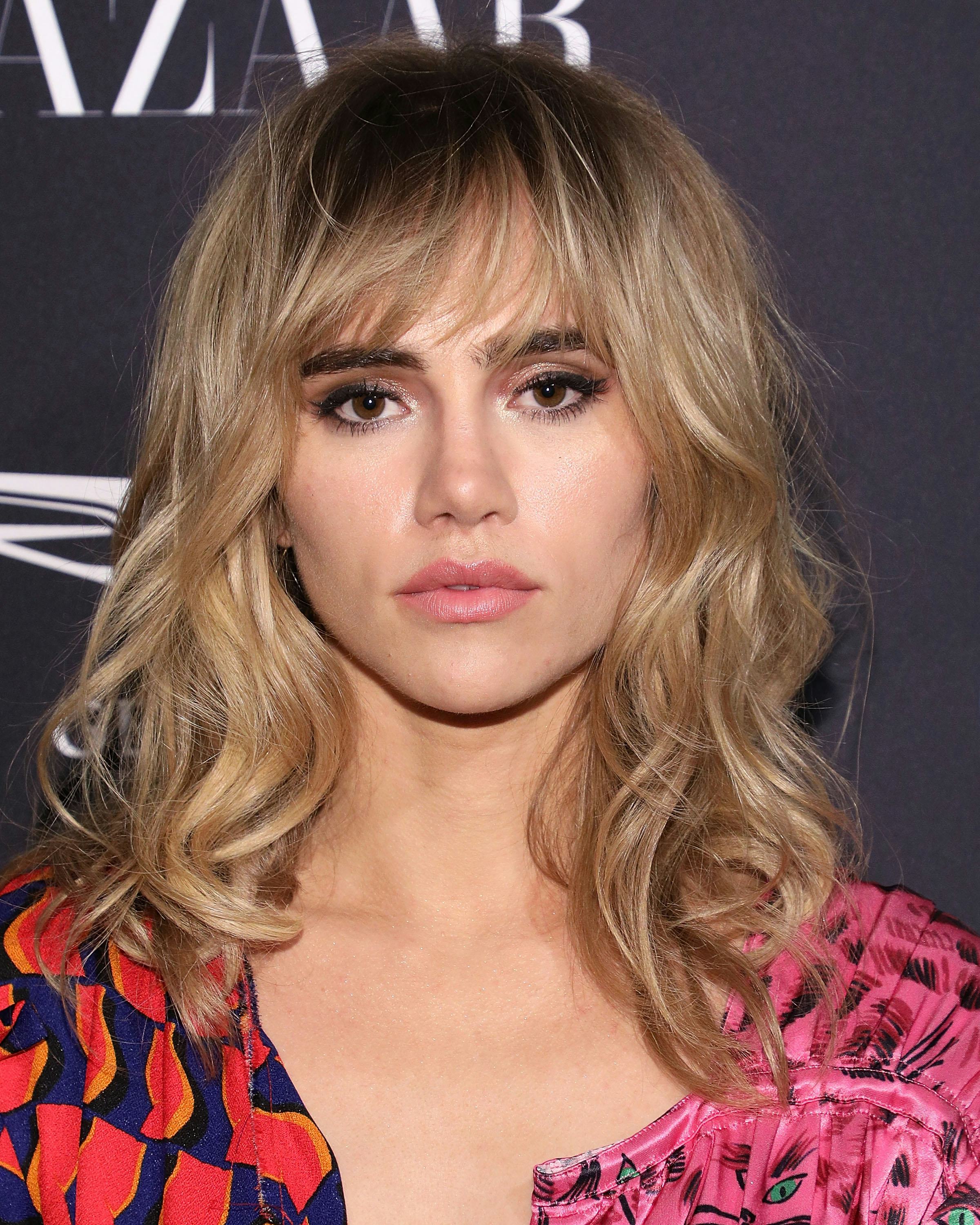 Suki Waterhouse wears her blonde hair in a &rsquo;70s-inspired shag with front fringe and waves.