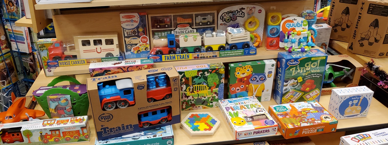 Photo of toy store display shelves packed with toddler toys, from toy vehicles to puzzles. 