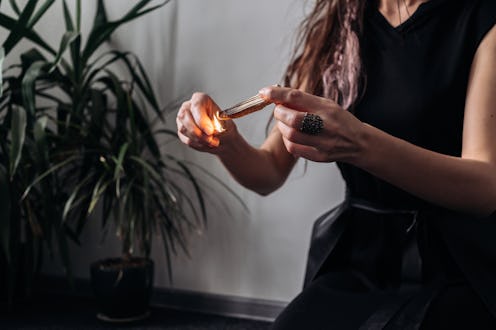 A woman wearing black dress performs a November new moon ritual to connect with the November New Moo...