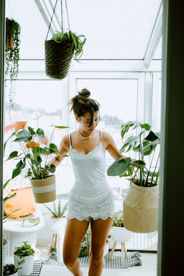 young female taking care of plants at home