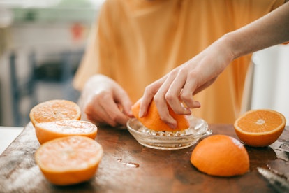 Boy squeezing oranges to make juice at the kitchen