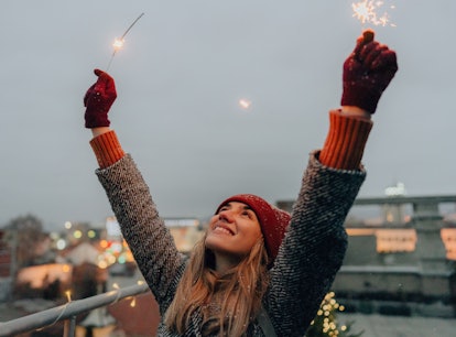Young woman holding sparklers during winter, thinking about how December 2021 will be the best month...