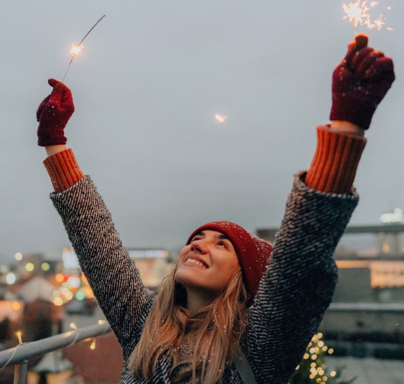Young woman holding sparklers during winter, thinking about how December 2021 will be the best month...