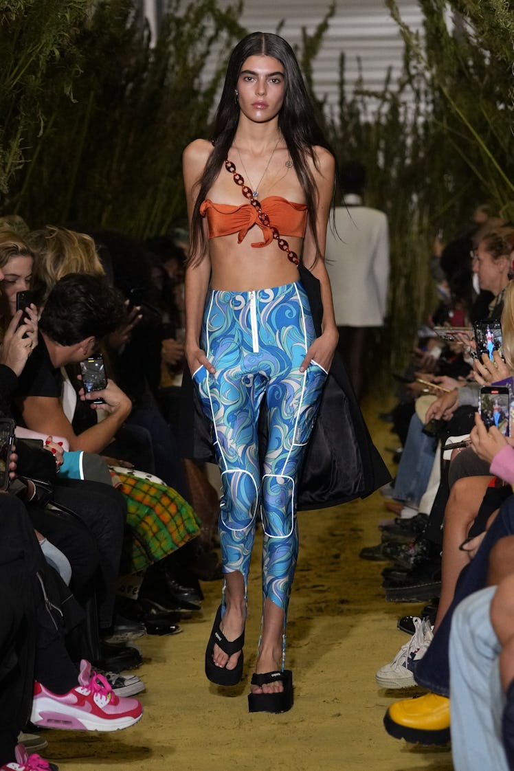 A model walking in an orange top and blue pants at the Coperni Womenswear Spring/Summer 2022 show