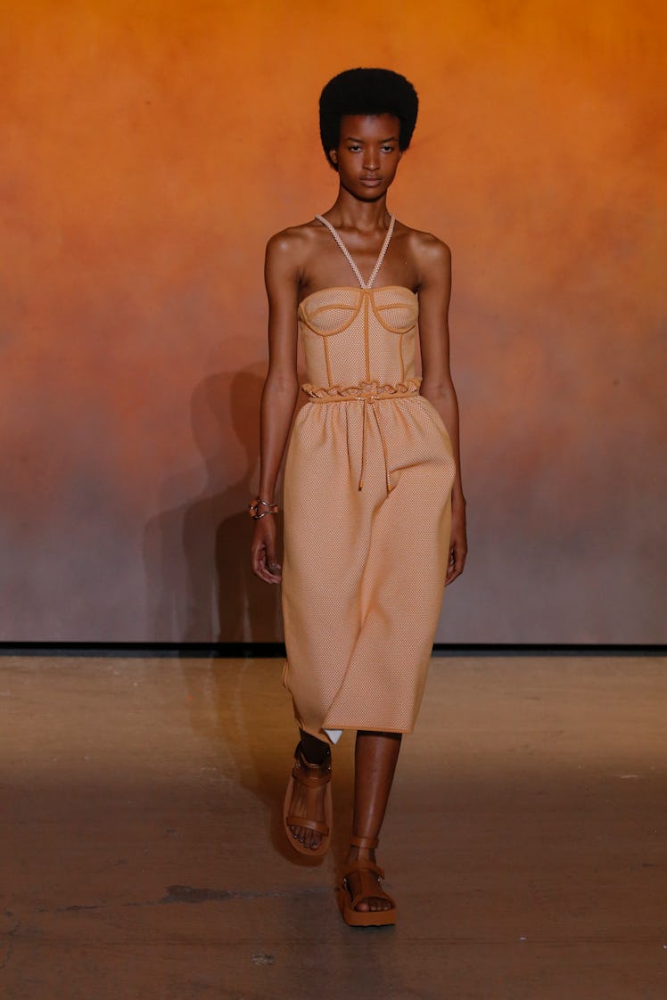 A model walking in an orange dress at the Hermes Ready to Wear Spring/Summer 2022 fashion show