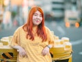 A young millennial generation woman is wearing a yellow t-shirt in the city.