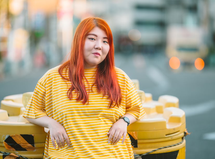 A young millennial generation woman is wearing a yellow t-shirt in the city.
