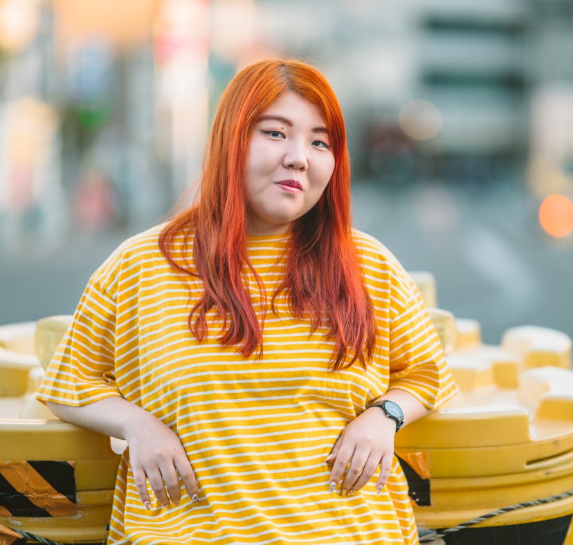 A young millennial generation woman is wearing a yellow t-shirt in the city.
