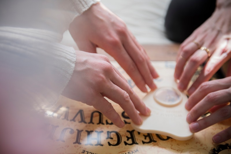 Young women use a Ouija board. The Ouija board's history and origins reveal much about the talking b...