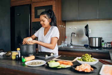 Skilled female sushi chef, making the rice balls for the Nigiri, in her modern domestic kitchen