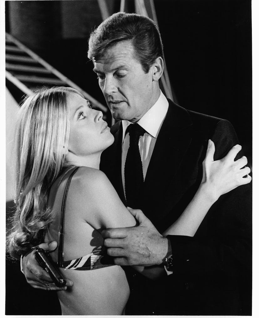 Roger Moore holds a gun as he embraces Britt Ekland who is wearing a bikini top in a scene from the ...