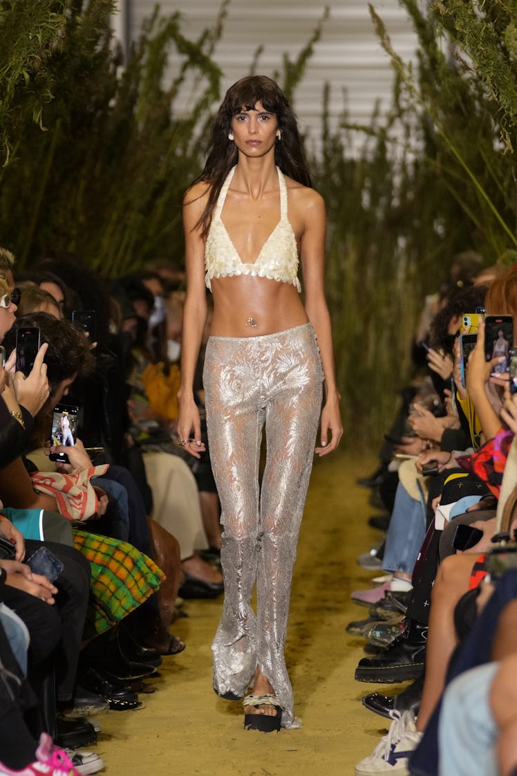 A model walking in an white top and pants at the Coperni Womenswear Spring/Summer 2022 show