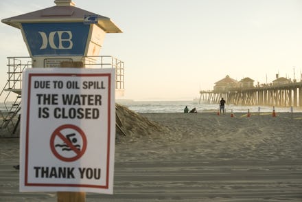 HUNTINGTON BEACH, CALIFORNIA - OCTOBER 03: A warning sign is posted near oil washed up on Huntington...