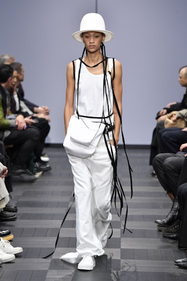 A model walking in a white shirt and pants at the Ann Demeulemeester Ready to Wear Spring/Summer 202...