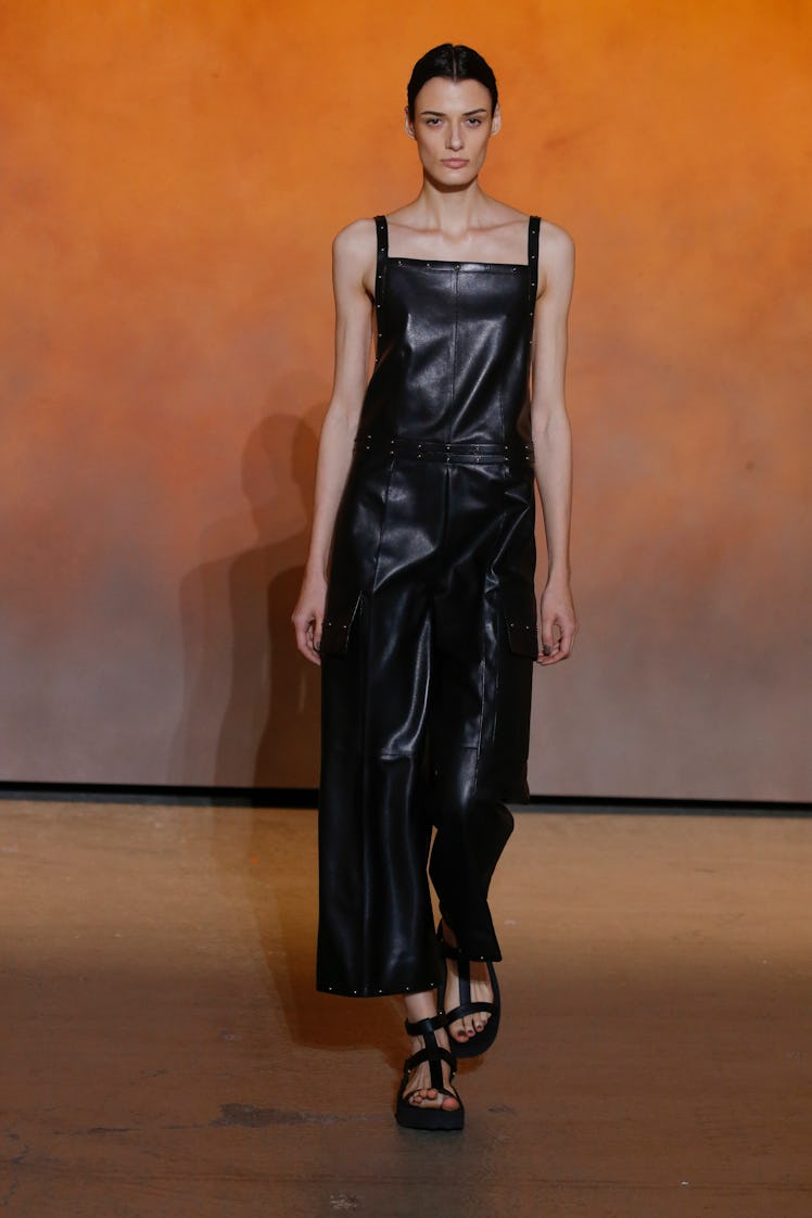 A model walking in a black leather jumpsuit at the Hermes Ready to Wear Spring/Summer 2022 fashion s...