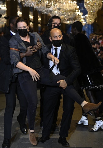 A demonstrator is being evicted by security members as models present a creation by Louis Vuitton du...