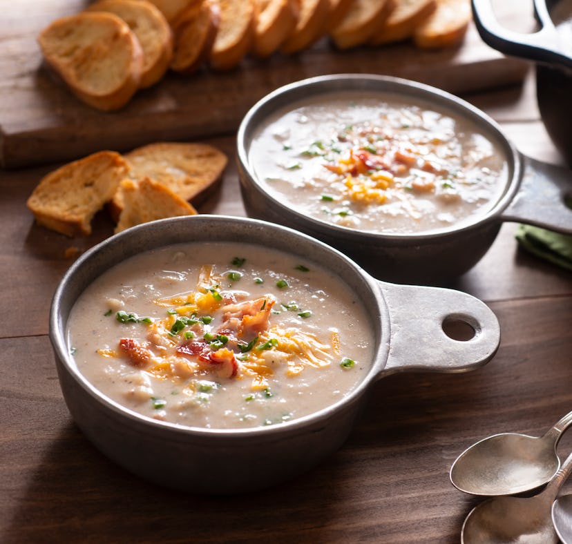 A bowl of TikTok's viral crockpot potato soup with bacon, cheddar cheese, and chives sits on the cou...