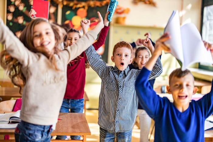 Large group of happy elementary students having fun while celebrating the end of a school year in th...