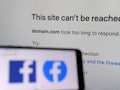 The Facebook logo displayed on a smartphone with a screen showing that Facebook service is down in t...