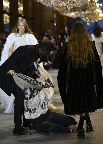 A demonstrator is being evicted by a security member as models present creations by Louis Vuitton du...