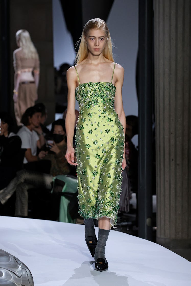 A model walking in a yellow dress with rhinestones at the Miu Miu Womenswear Spring/Summer 2022 show...