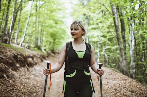 Portrait Of Smiling Female Hiker Enjoying Walking Through Forest